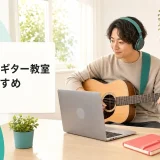 オンラインギター教室おすすめのヒーロー画像。ヘッドホンを着けたギター初心者がノートPC越しに講師のレッスンを受けながら、隣のスマホ三脚で手元を録画している明るいリビング